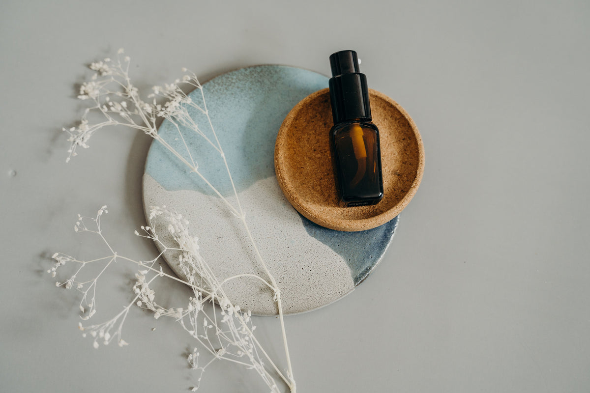 Flacon de soin cosmétique sur assiettes en céramique avec fleurs séchées